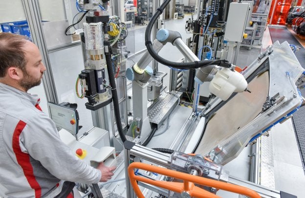 Un operario trabaja junto a un robot, en la planta de Audi.