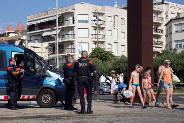 Turistas pasean ante la presencia de los Mossos d'Esquadra en el paseo marítimo de Cambrils. :: reuters