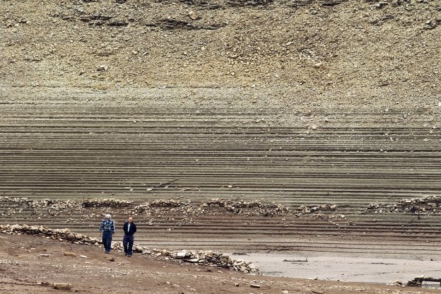 Dos personas pasean por el lecho del embalse de Mansilla este lunes. :: justo rodríguez