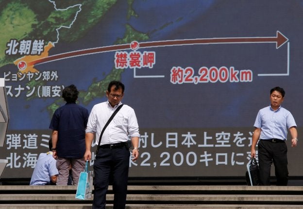 Transeúntes pasan frente a una pantalla gigante que describe la trayectoria del misil norcoreano en Tokio. :: reuters