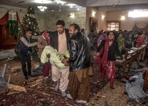 Varios hombres se llevan a heridos tras el atentado durante la preparación de los actos de Navidad dentro del templo de Quetta, en Pakistán. :: A. CALVIN / AFP/
