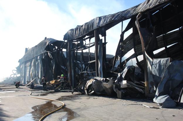 Los bomberos del CEIS-Rioja van atacando metro a metro el interior de la nave calcinada, pues pequeños focos de fuego aún se consumen bajo las paredes y cámaras afectadas. :: /Ernesto Pascual