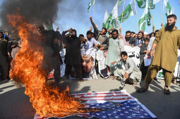 Manifestantes queman una bandera americana en Karachi. :: afp/