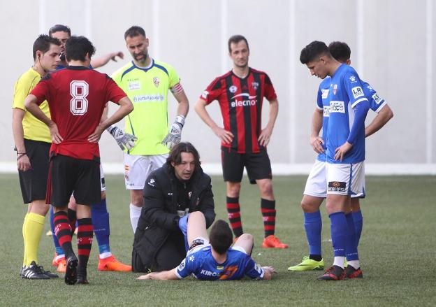 José Miguel Martín, fisioterapeuta de la UDL, explora la rodilla izquierda de Álvaro Arnedo sobre el césped de Gobela. :: fernando díaz/