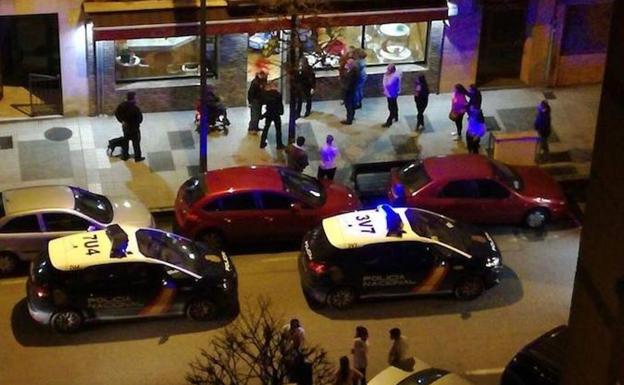 Dos patrullas de la Policía Nacional, junto a clientes del bar y vecinos, a las puertas del local. / E.C.