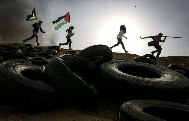 Palestinos colocan neumáticos en la frontera con Israel, a los que prenderán fuego para afectar el trabajo de los francotiradores. :: reuters/