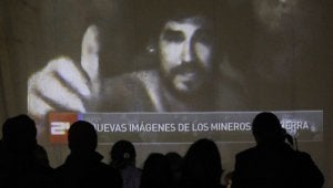 Familiares de los mineros visionan el vídeo grabado en el yacimiento en una pantalla en el campamento Esperanza. :: REUTERS/