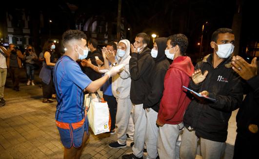 Un vecino de la capital grancanaria reparte comida a los inmigrantes que el martes fueron sacados del muelle y abandonados a su suerte./C.S.A.